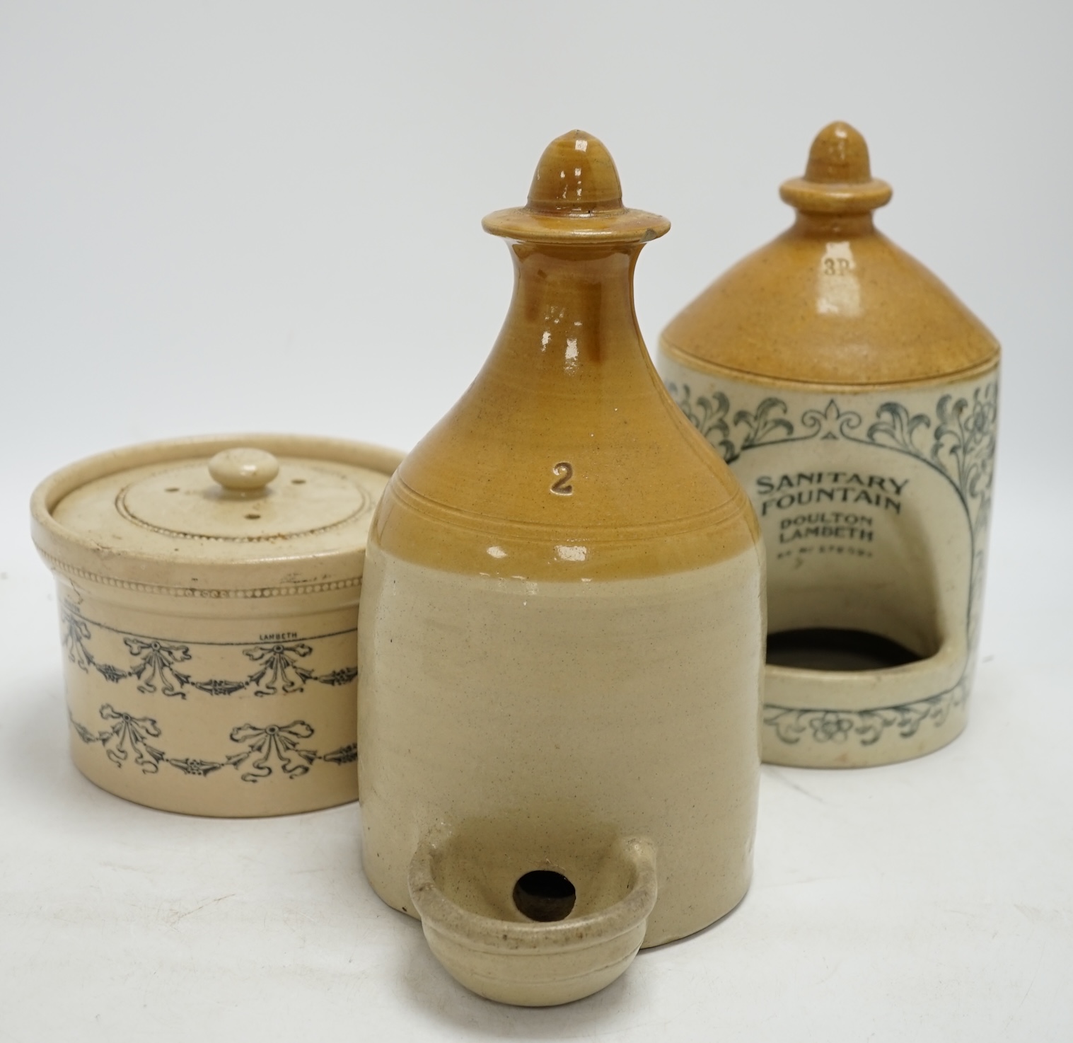 A late Victorian Doulton Lambeth Sanitary Fountain feeder, another similar, and a circular jar and cover, sanitary feeder 25cm high. Condition - sanitary feeder good, other feeder chipped and cover to jar chipped